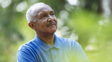 An older man outside looks into the distance, thinking.