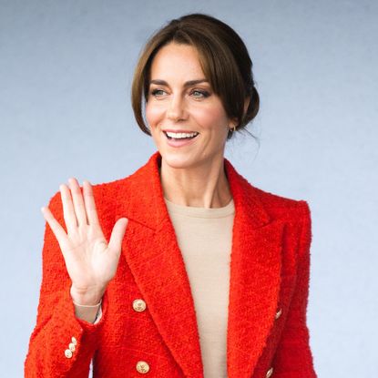 Kate Middleton in a red blazer smiling and waving