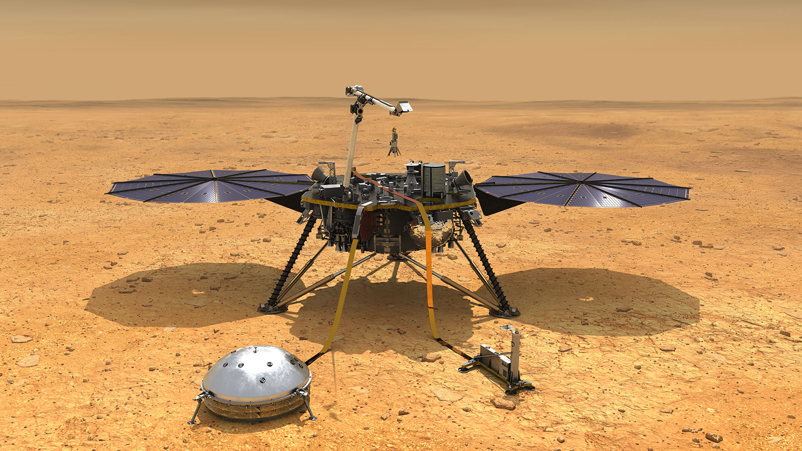 A spacecraft with two solar wings is seen on an arid, orange and brown ground.