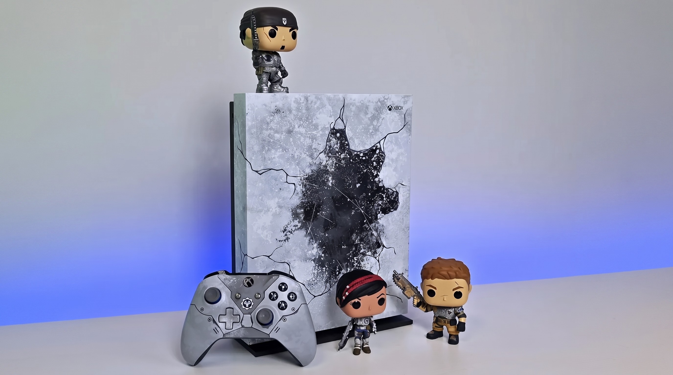 A photo of a special edition Gears of War Xbox One X and matching controller with three Gears of War Funko Pop figures. 