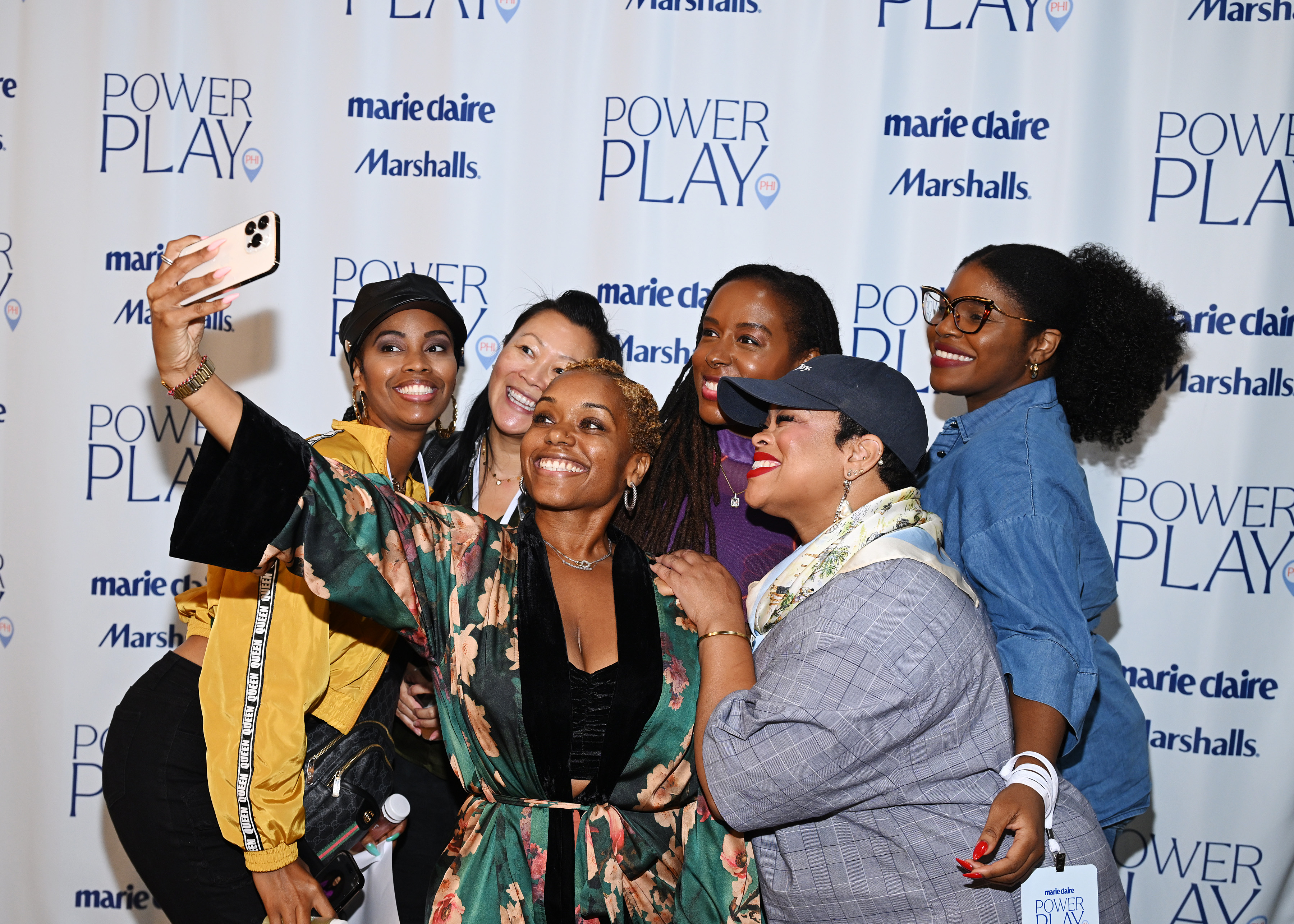 A group of women pose together for a selfie in front of the Marie Claire Power Play and Marshalls step-and-repeat backdrop in Philadelphia.