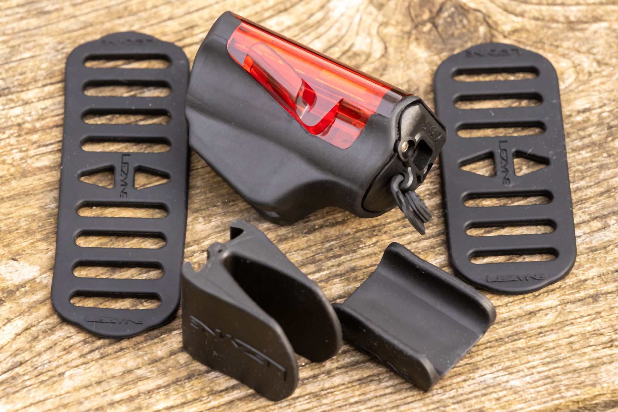 Lezyne Radar Drive Rear pictured off bike, on a wooden surface, with straps and rubber shims for seat posts.