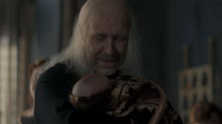 King Viserys looking ancient and holding Rhaneyra's new baby.