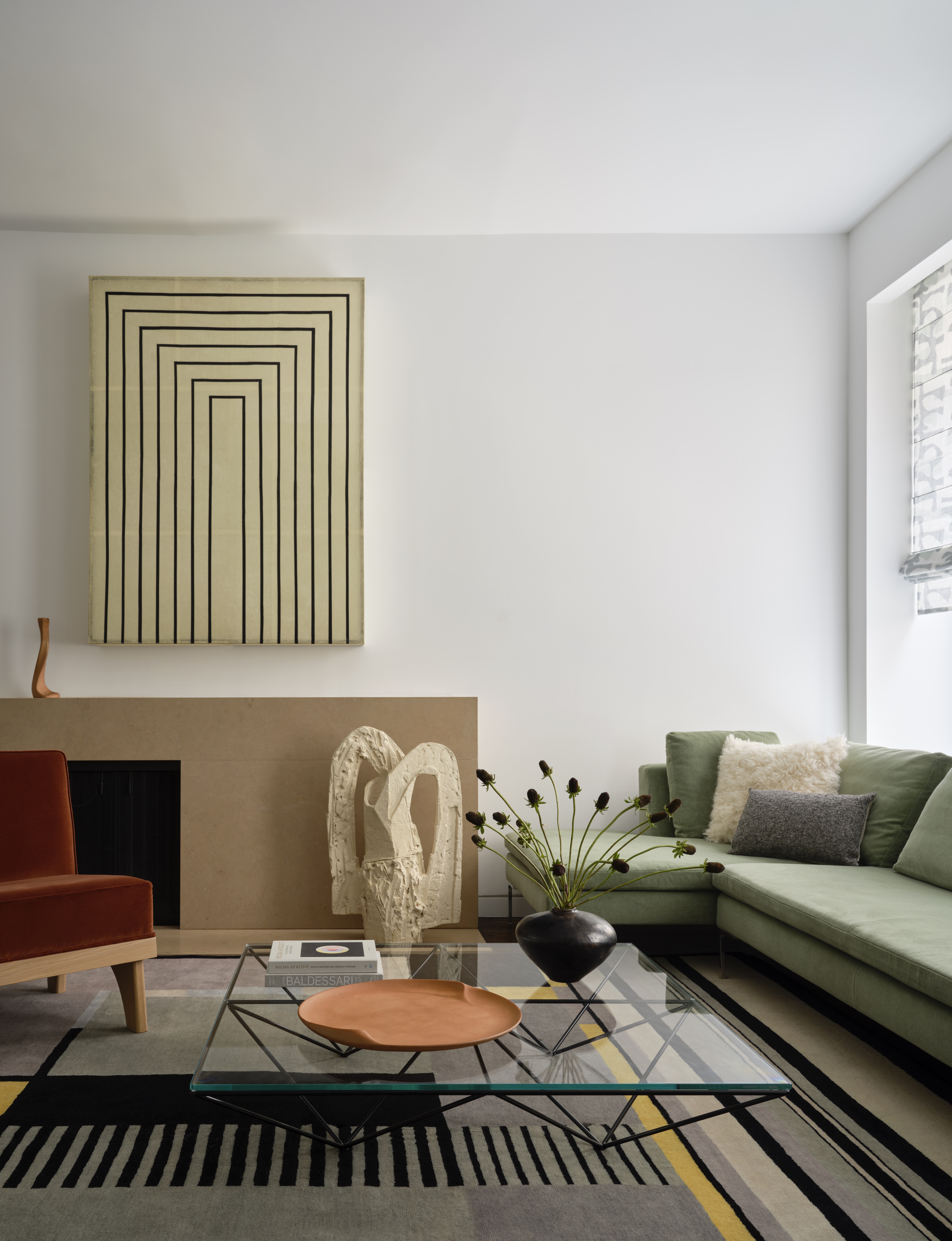 A living room with a geometric-design rug, a green sectional and a red armchair