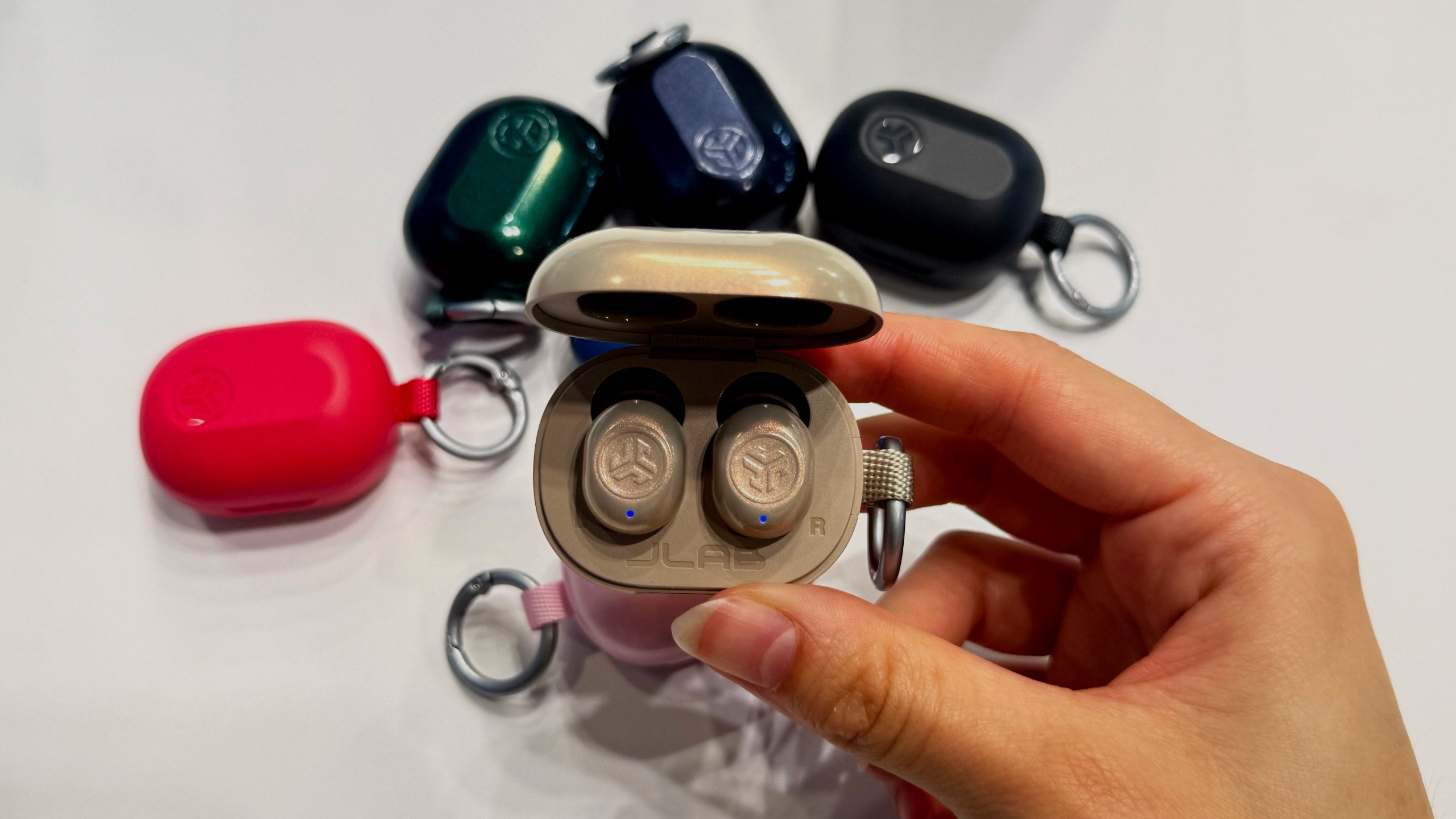 the jlab jbuds mini anc in champagne photographed with five pairs in the background