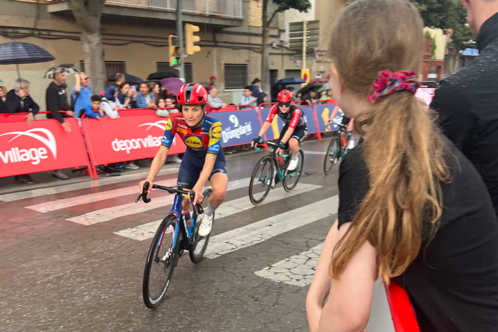 Lizzie Deignan on her bike being cheered on by girl with her back to the camera