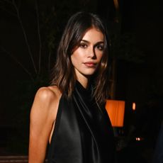 Kaia Gerber wears a black outfit and has shoulder length brunette hair