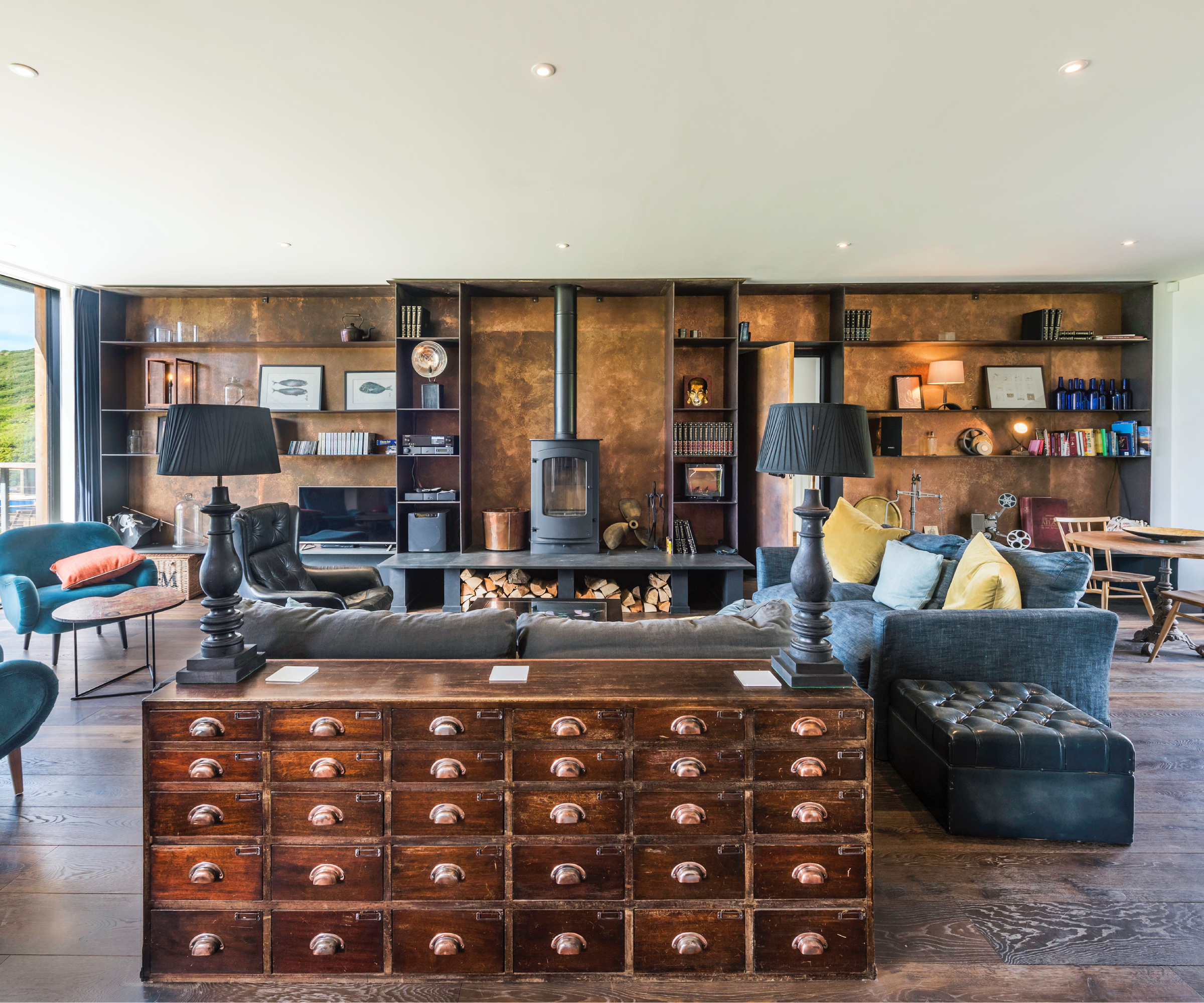 dark oak floor in open plan living room with log burner, sofas and large wooden chest with drawers