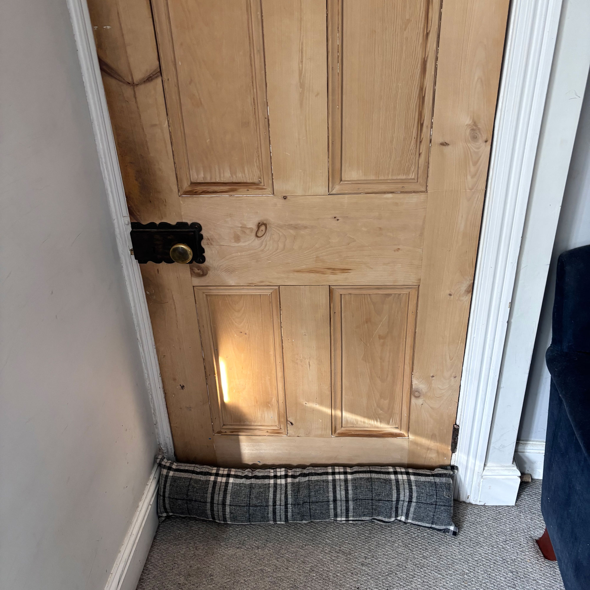 pine four panel door with grey tartan draught excluder