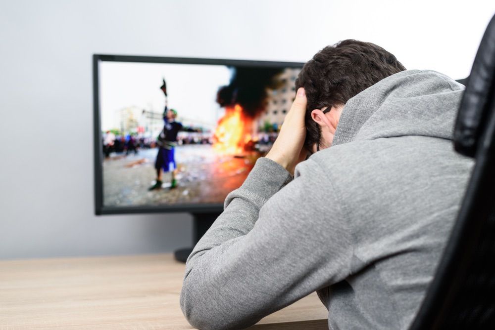 troubled man watching (on TV) news about civil riots, aggressive protesters