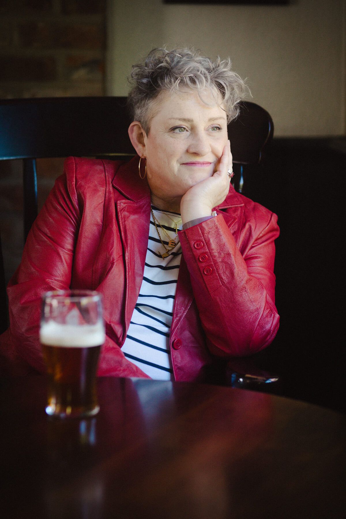 Portrait of woman in a pub posing with head rested in palm of hand.