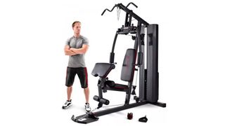 Marcy Club 200 Gym review: an image showing a man standing next to the Marcy home gym
