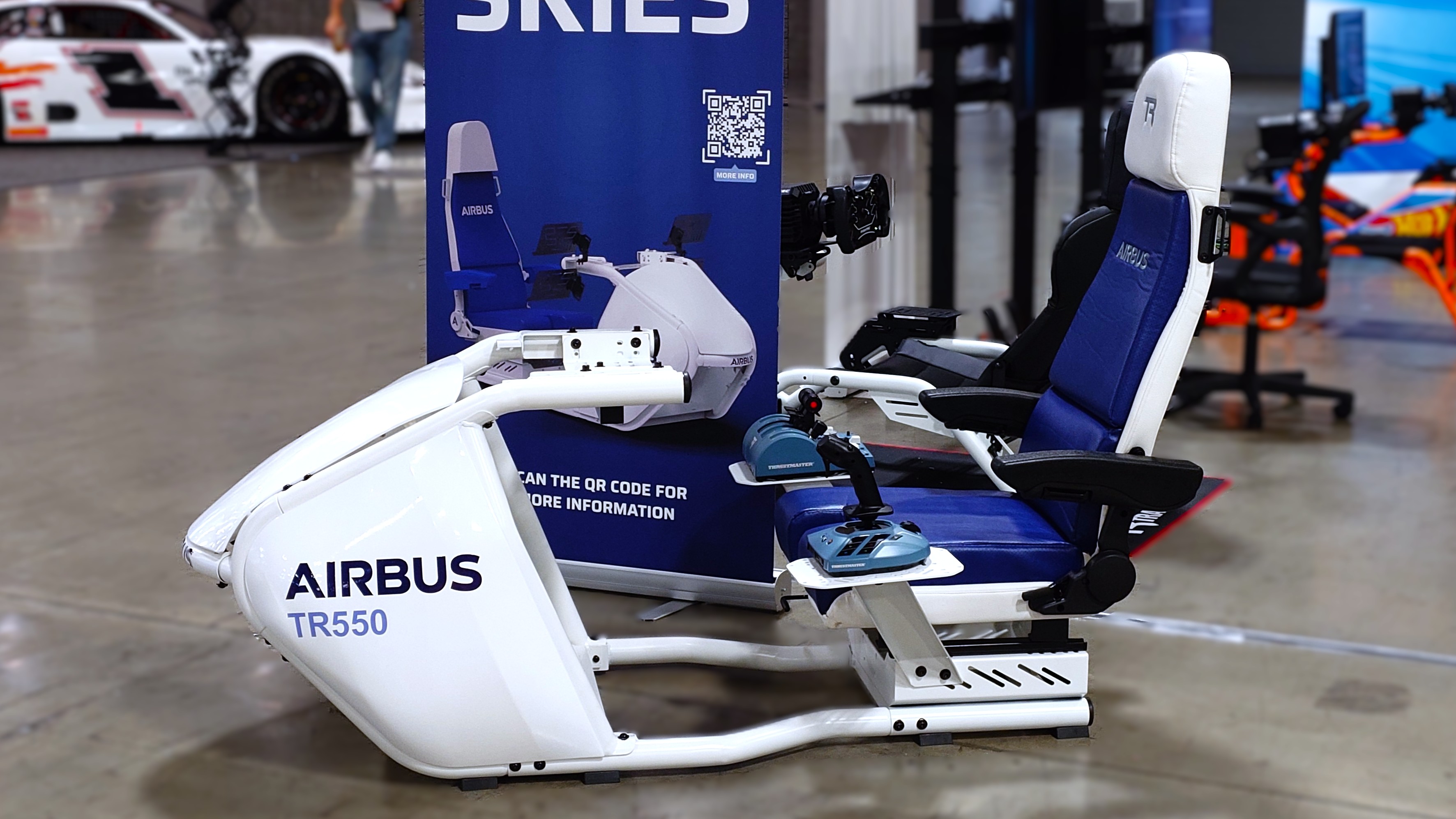 A side-on photograph of the Trak Racer TR550 flight simulator cockpit in white and blue showcasing the Airbus logo and Airbus licensed flight controllers. 