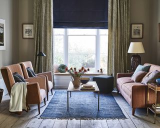 George Spencer designs illustrating cozy living room ideas in a dark gray scheme with red gingham sofa and chairs and blue rug.