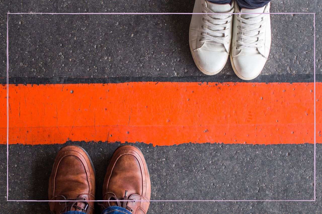 Two pairs of feet stood either side of a red boundary line