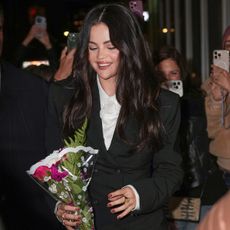 Selena Gomez wears a white blouse and a black mini blazer dress.