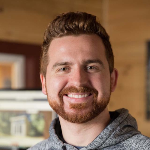 Close-up image of a man with a beard in a gray hoodie