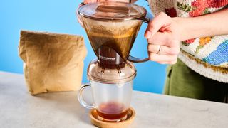 the clever dripper, a brown transparent plastic manual coffee maker with a handle and a sluice feature in the bottom to keep water inside