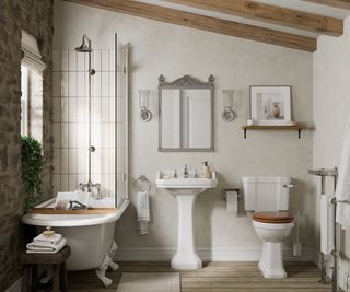bathroom with exposed stone wall, wooden flooring and classical white sink, bath and toilet