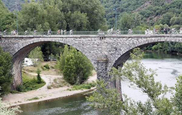 The peloton passes over a scenic bridge.