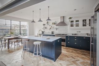 blue kitchen with white work tops and dining area in extensions