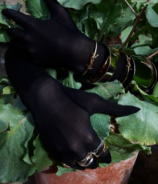 Gloved hands wearing Saint Laurent fine jewellery rings and bracelets