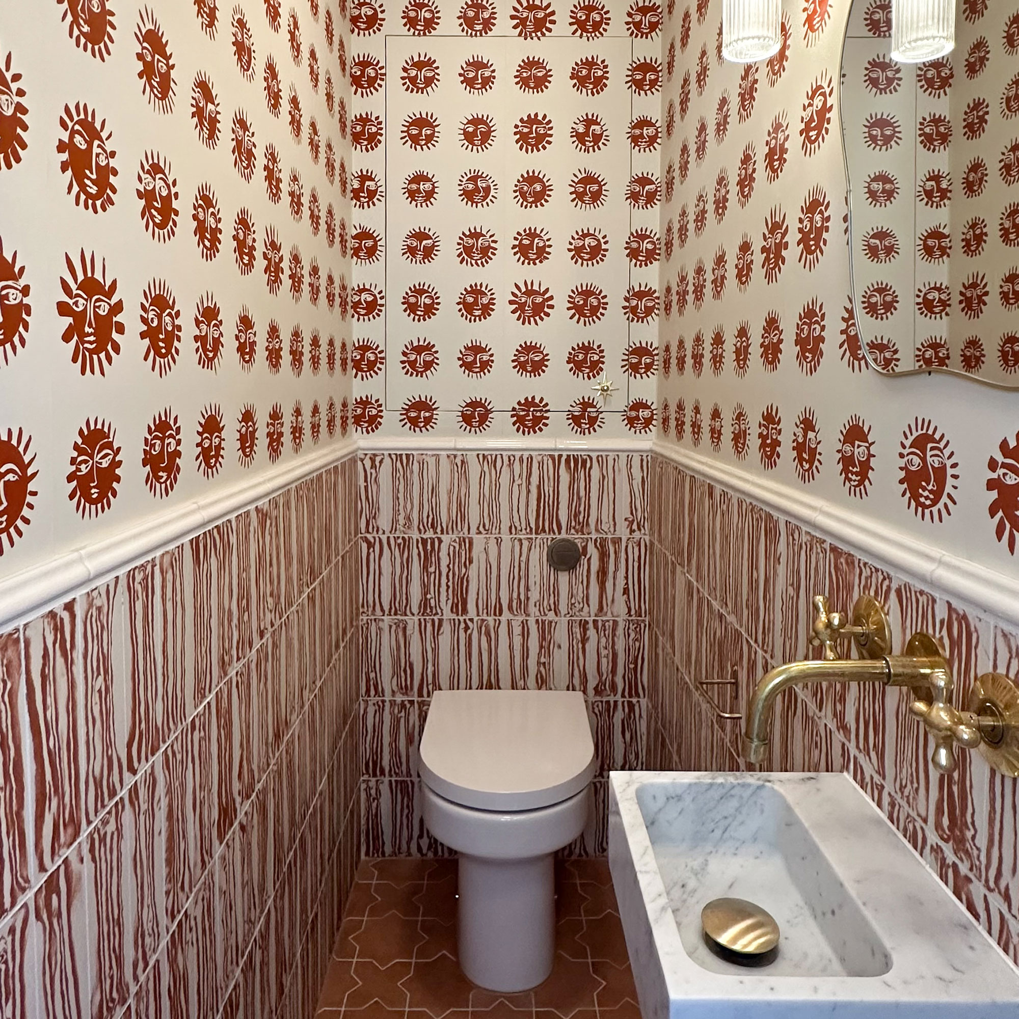 Small bathroom with walls in half red and white abstract striped tiles and half red and white sun patterned wallpaper