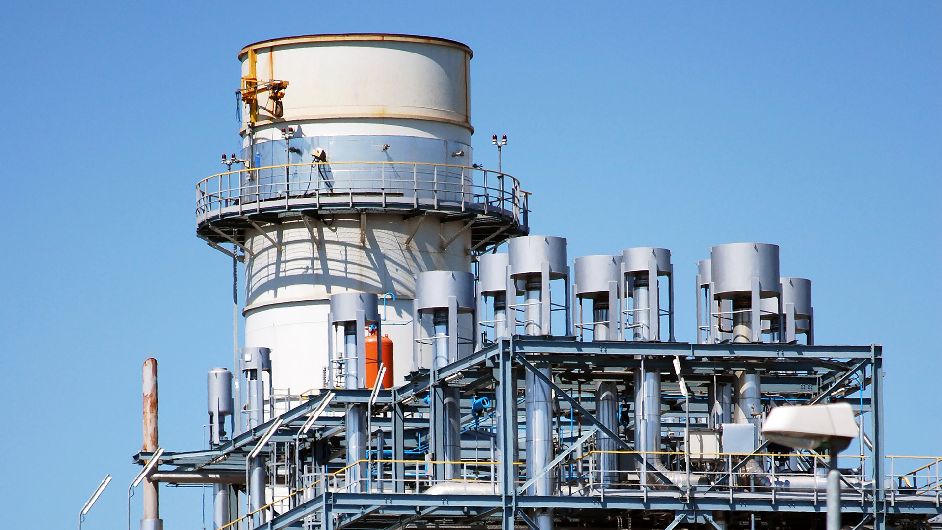 A telephoto shot of a gas power plant, against a blue sky.