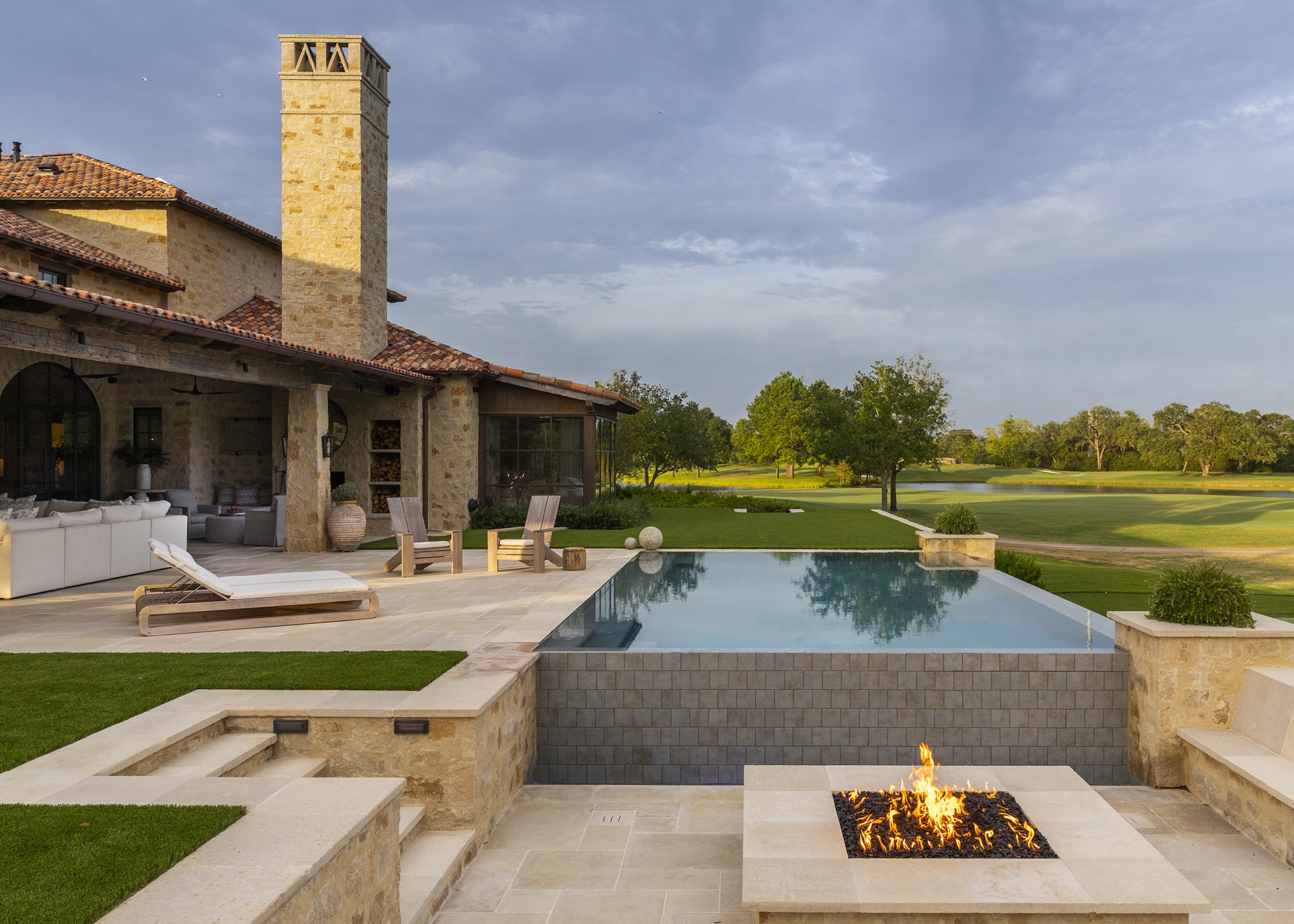 Outdoor terrace with swimminh pool and tiered landscaping with sunken firepit