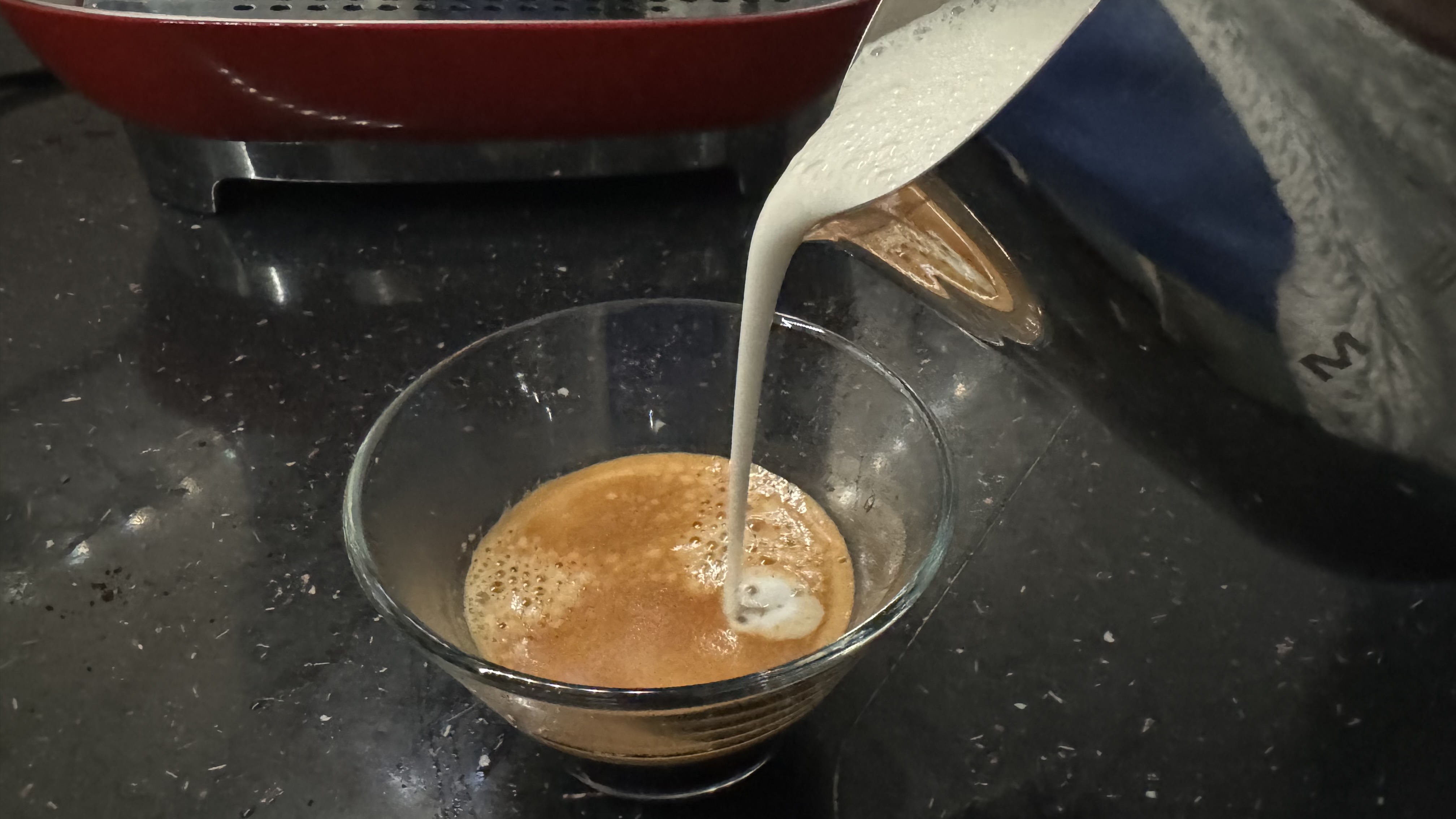 Frothy milk being poured into espresso made by the Smeg Espresso Coffee Machine EGF03