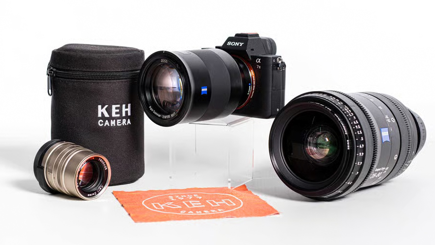 Zeiss lenses and a Sony camera on a white surface next to a KEH lens cloth