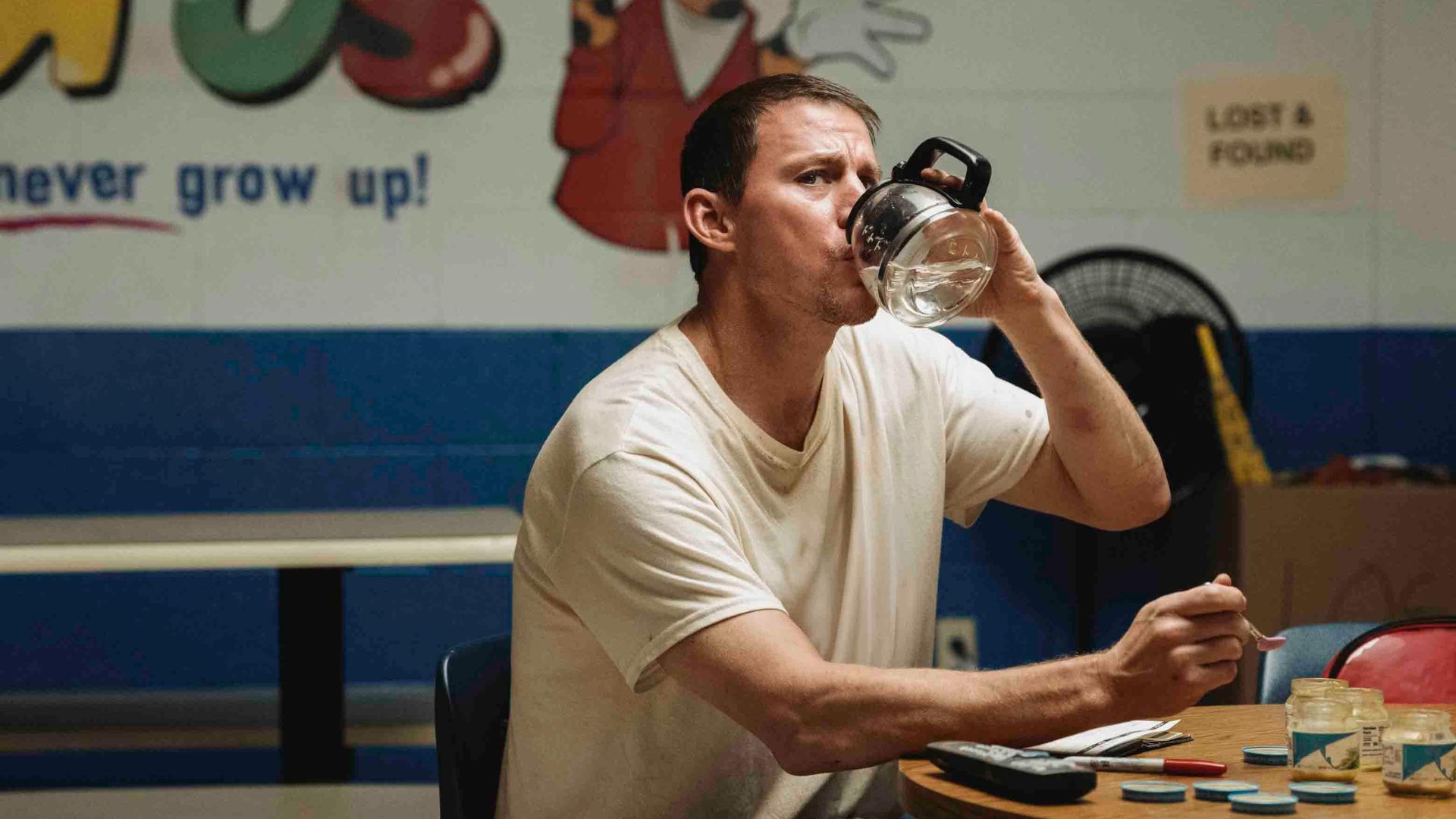Channing Tatum drinks out of a coffee vat while holding a baby food spoon