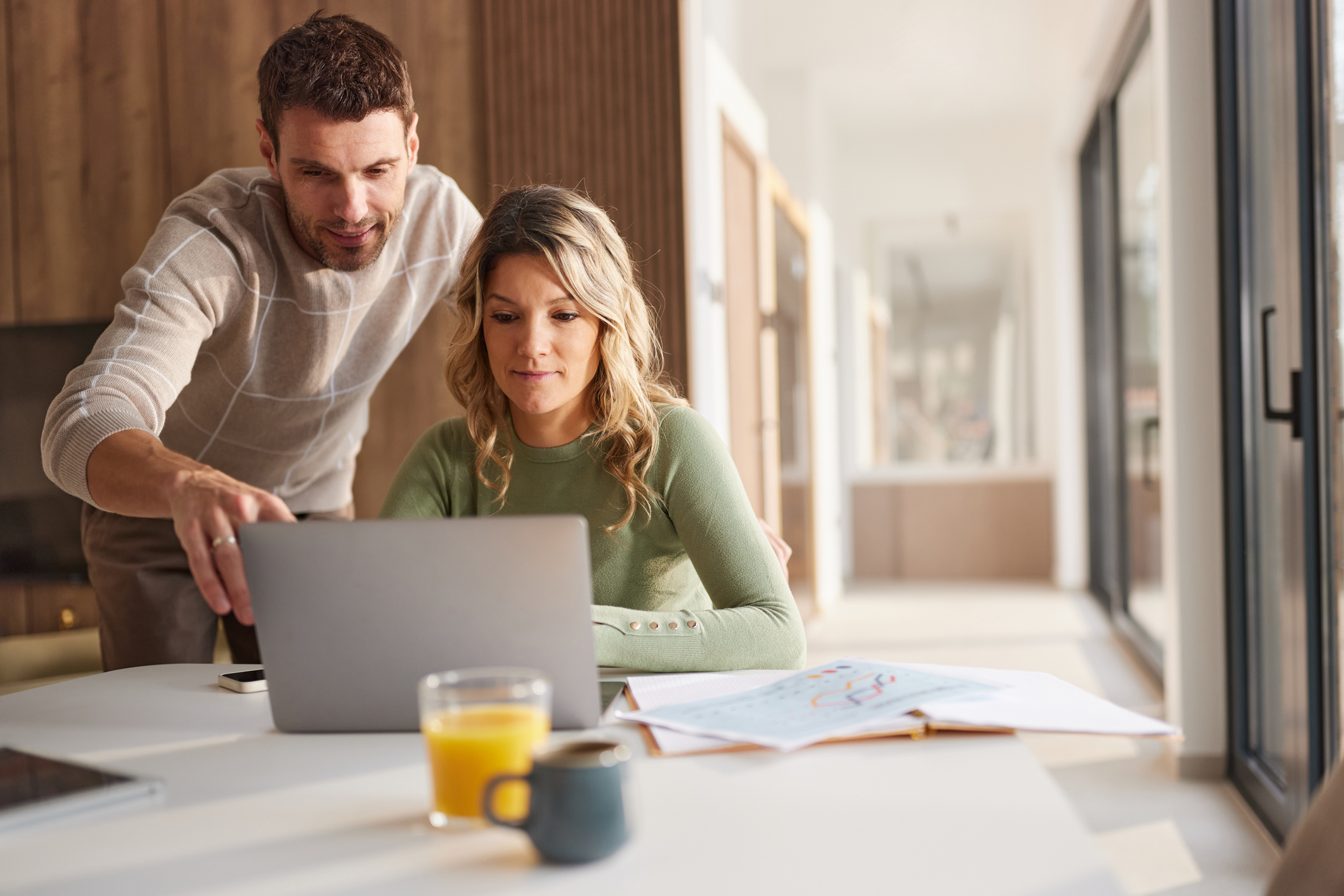 Mid adult couple working on laptop at dining table
