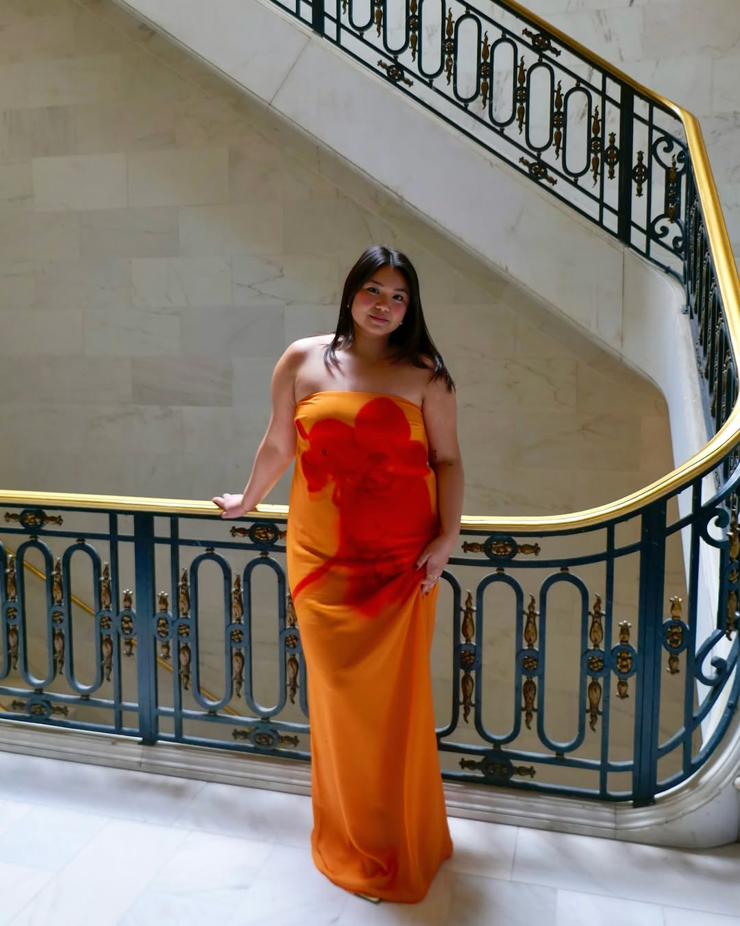 Marina in an orange dress with a red flower printed on it