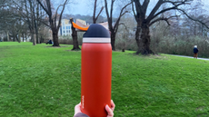 a burnt orange terracotta owala freesip 32oz water bottle photographed with greenery and trees