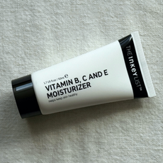 The INKEY List Vitamin B, C and E Moisturiser laying at an angle on an off-white linen background 