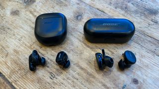 Bose QuietComfort Earbuds II buds and case next to Bose Sports Earbuds buds and case