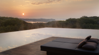 A poolside terrace at Amanemu at sunset