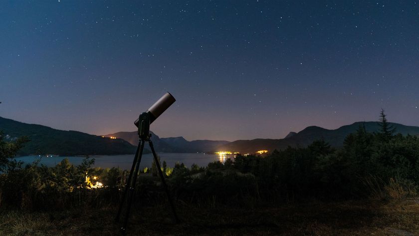 A Unistellar smart telescope with the backdrop of a lake and mountains at night.