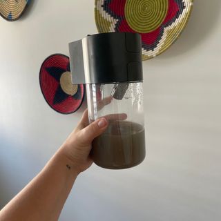 Dirty water tank filled with brown water in front of colourful wall baskets