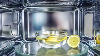 bowl of water and lemons in microwave oven as an natural hack for how to clean an oven