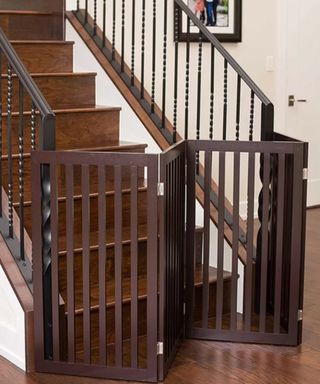 A dark brown tall dog gate used at the bottom of stairs