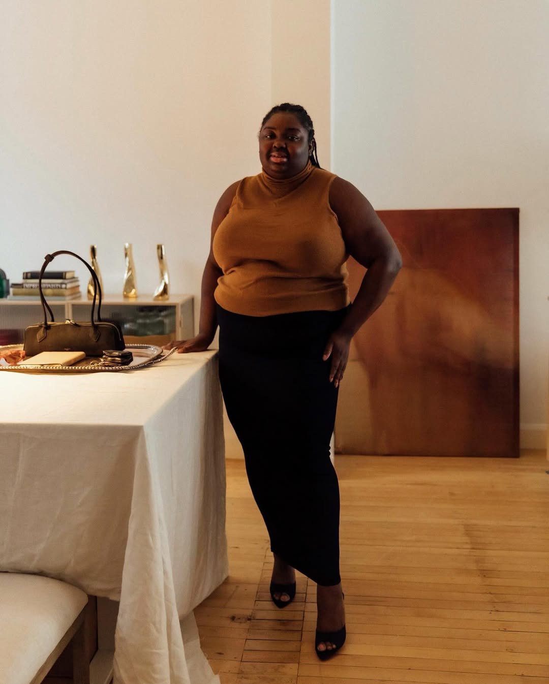 Abisola in a black pencil skirt and orange top
