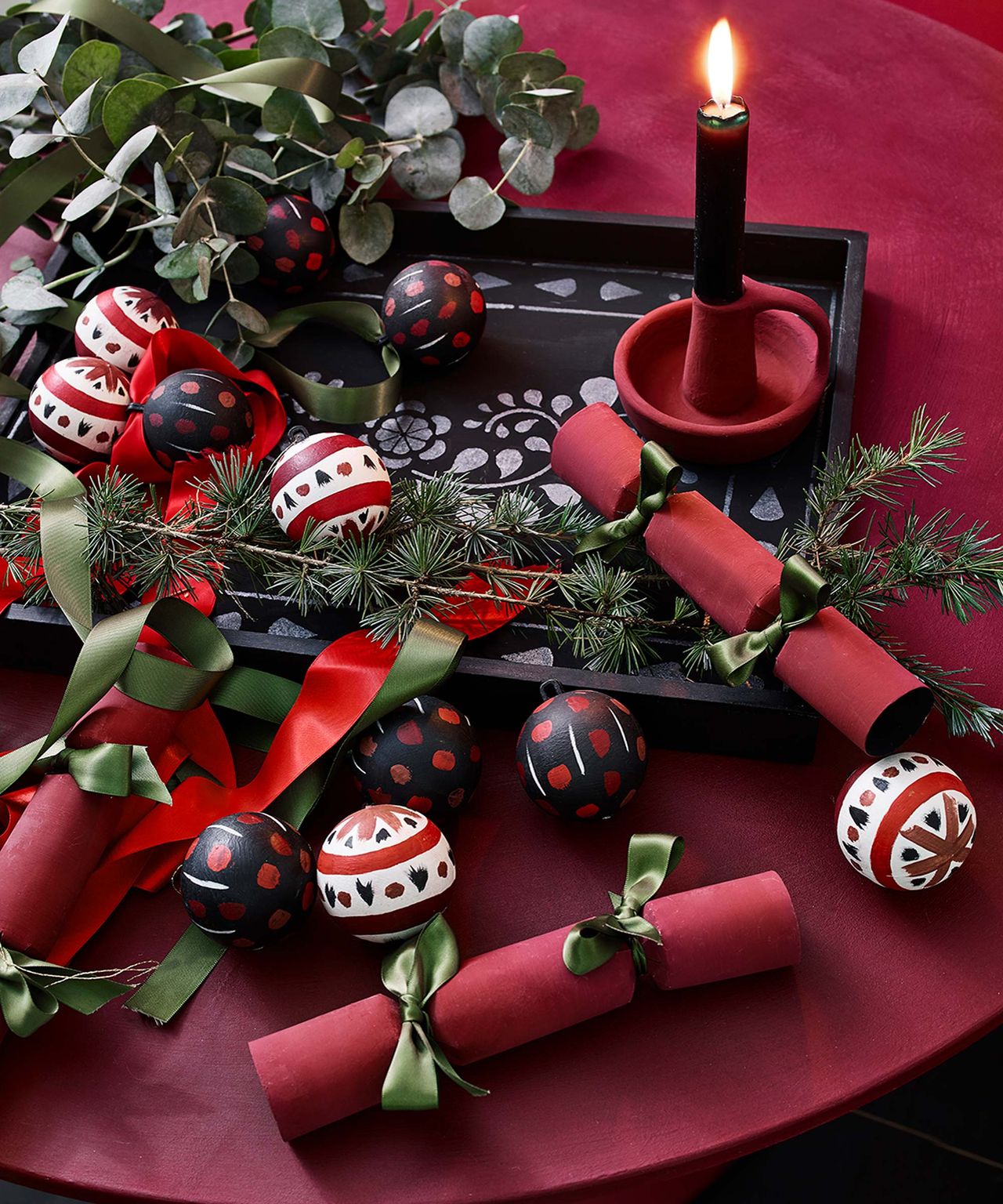 Red Christmas crackers and ornaments with festive foliage on a red table