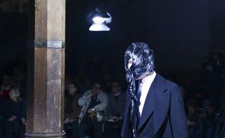 Male model with long black hair pulled in front of his face