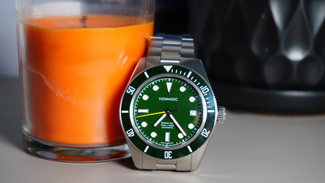 The Nomadic Marai 401 in Emerald Abyss against an orange candle