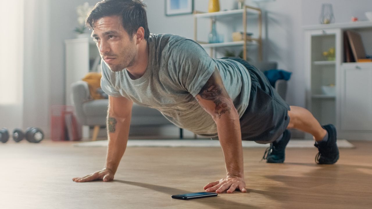 A man performing a push-up as part of a bodyweight workout at home 