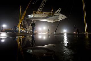 The space shuttle Discovery is suspended from a sling held by two cranes shortly after the NASA 747 Shuttle Carrier Aircraft (SCA) was pushed back from underneath at Washington Dulles International Airport.