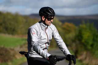 Stationary rider sitting on his top tube wearing the Castelli Tempesta Lite jacket