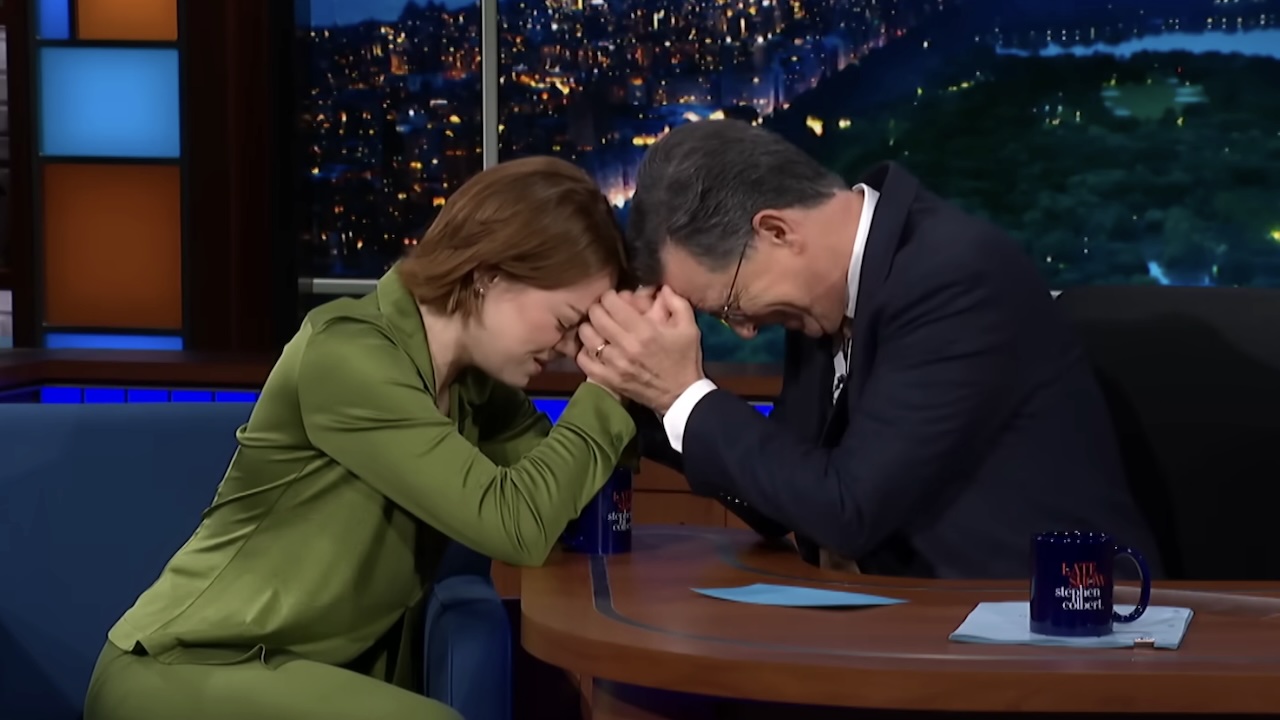Emma Stone clasping hands with Stephen Colbert on The Late Show with Stephen Colbert